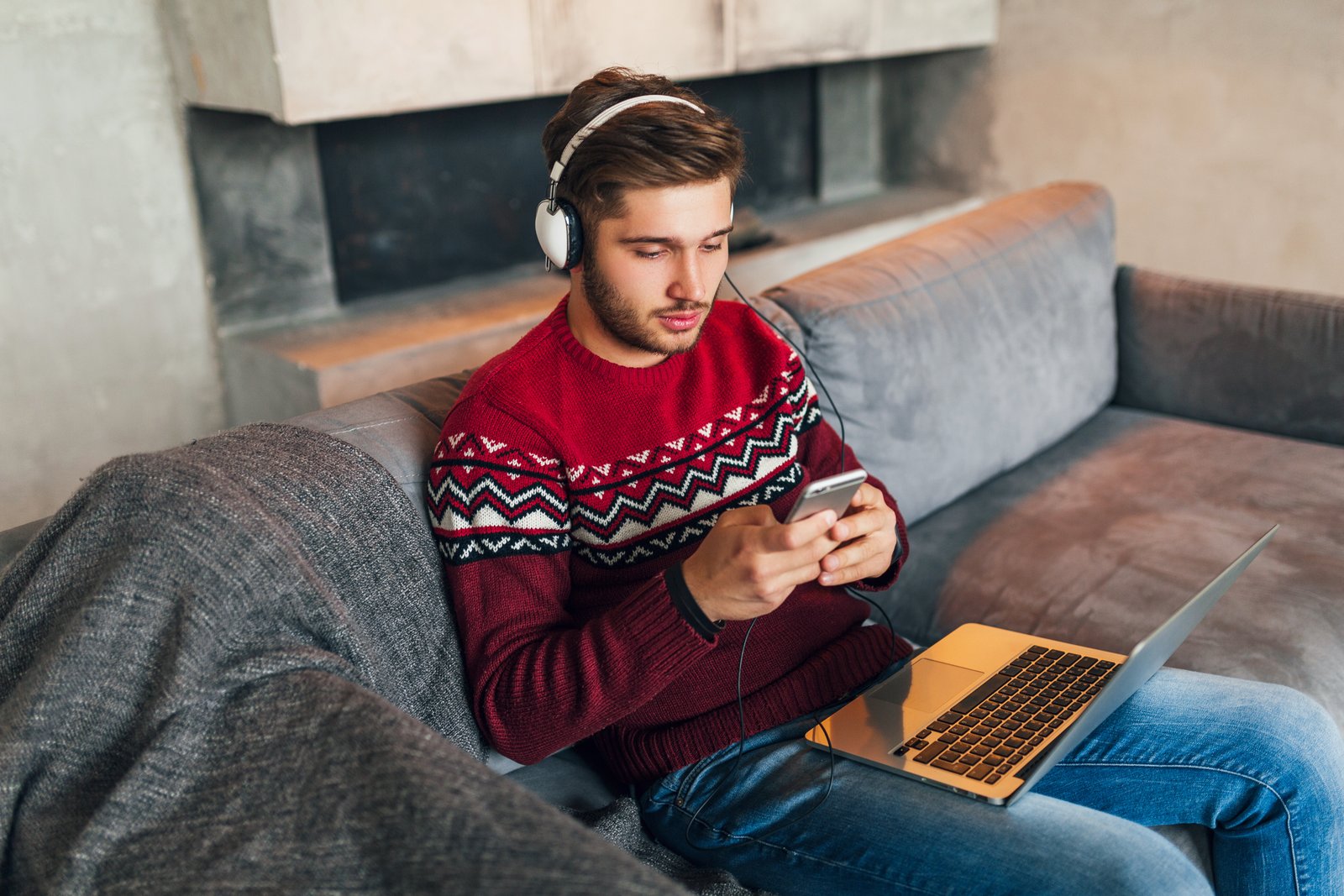 closeup man lying couch home with headphones listening podcast his smartphone